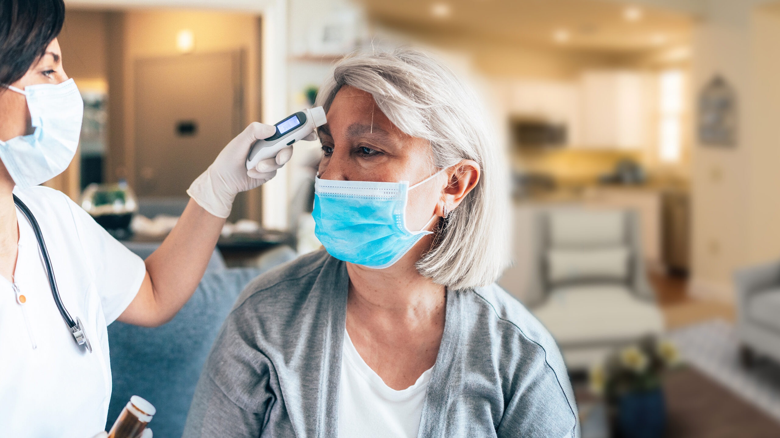 Nurse taking temperature of senior resident