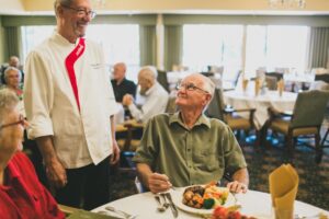 Man sitting in a restaurant with a full plate of food, smiling up at the waiter