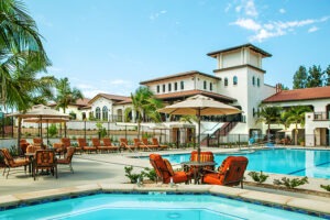 Pool and Jacuzzi with surrounding tables and chairs and chaise lounges