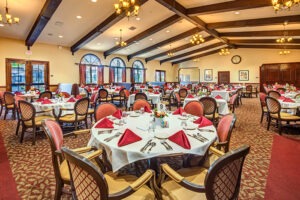 Indoor banquet room with several large circular tables covered in white tablecloths