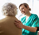 Nurse helping senior and patting her back