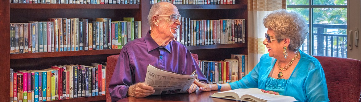 Man and woman sitting in community library reading newspapers