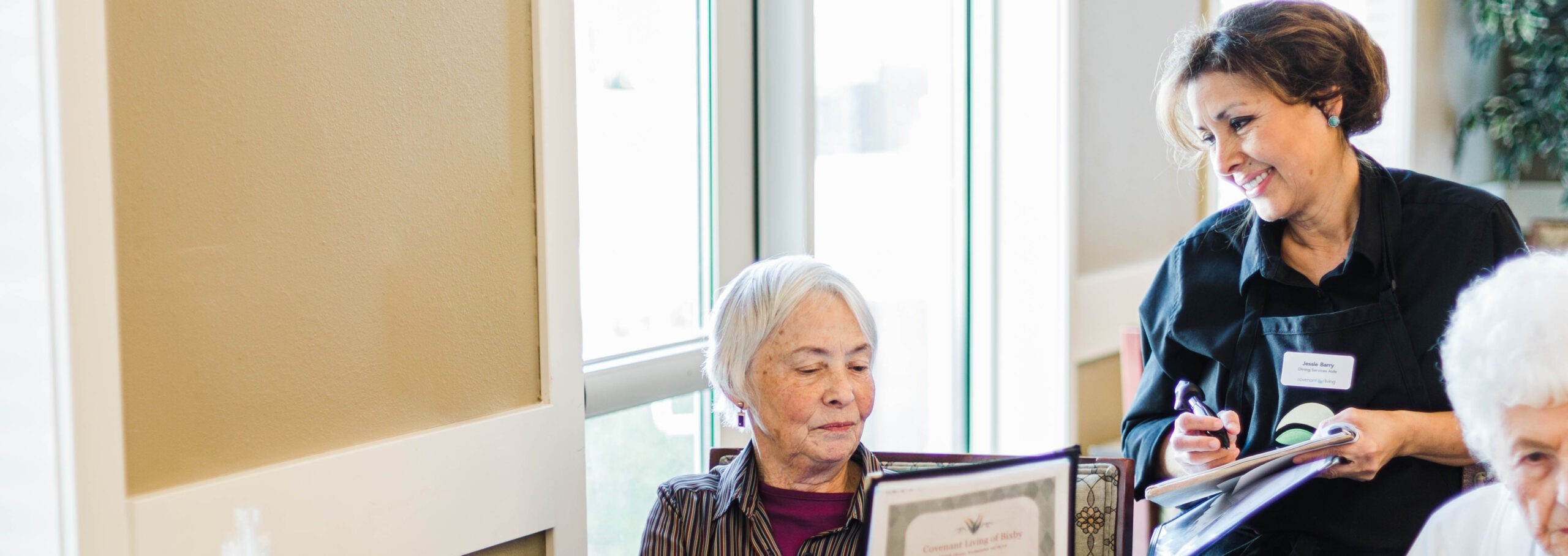 Nurse assisting senior resident and reviewing documents