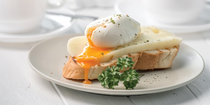 Poached egg leaking yolk on top of cheese and toast