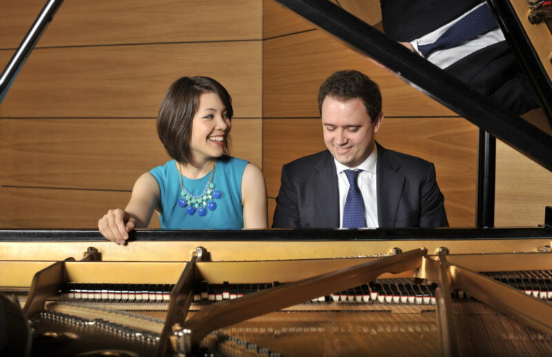 Man and woman sitting at a piano playing together and smiling